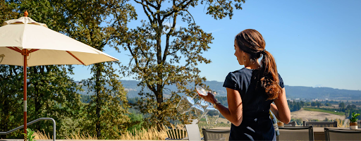 A woman holding a wine glass with rolling hills in the background.